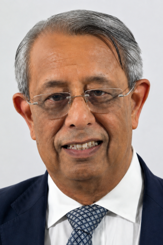 Headshot of Mukesh Chawla smiling while standing in front of a white wall.