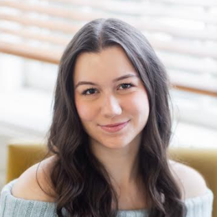Student Research Assistant Yuliya Velhan smiles at camera while sitting in a chair in an office setting.