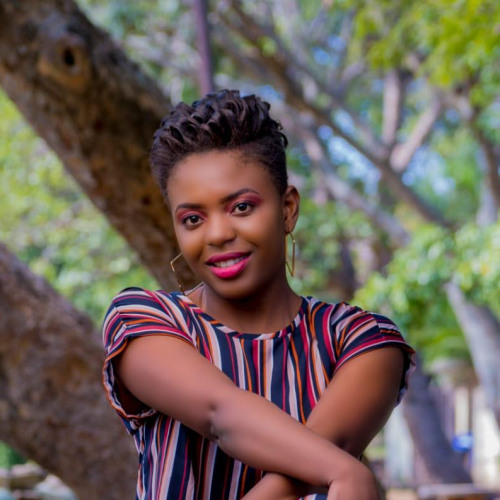 Joyce Fati Masvaya sits by a tree outside for her headshot photo in a park
