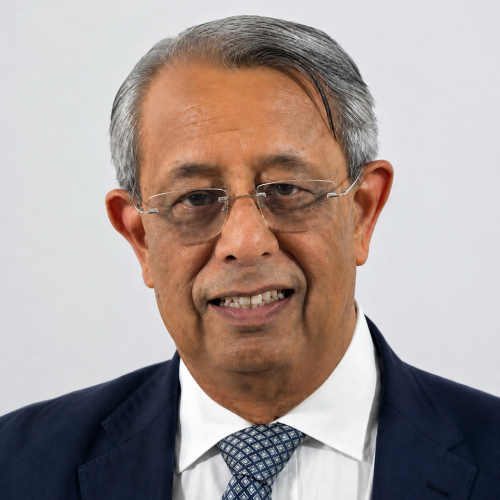 Headshot of Mukesh Chawla smiling while standing in front of a white wall.